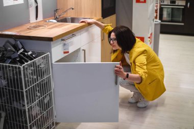 Mutfağın planlanması. Genç kadın ev hanımı mağazada satın almak için mutfak mobilyaları seçer. Satış kavramı