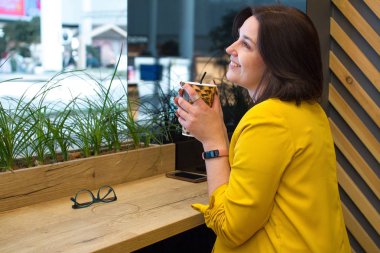 Kız leopar baskılı bir kağıt Fincan ve sütlü kahve tutar. Kafede satın almalar arasındaki aralık.