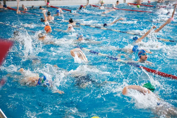 Rusland, Novosibirsk, 26 mei 2019. Zwemwedstrijden begonnen. Veel kinderen zwemmen en spetteren zwaar in het zwembad. Opwarmen voor de race. — Stockfoto