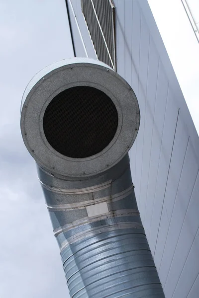 Ventilation pipe. One round industrial ventilation pipe on the roof of the building against the sky.