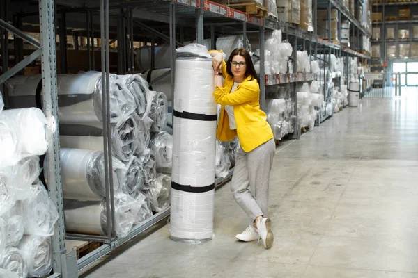 Meisje met bril neemt een groot en zwaar matras in de winkel. Groothandel en aankoop. Self-service magazijn. Selectie van producten — Stockfoto