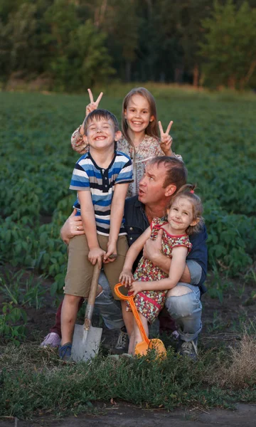 Drie kinderen met zijn vader die plezier hebben in het veld. Het concept van het begin van de bouw van het toekomstige huis, de heropleving van de landbouw, een vriendelijke familie. — Stockfoto