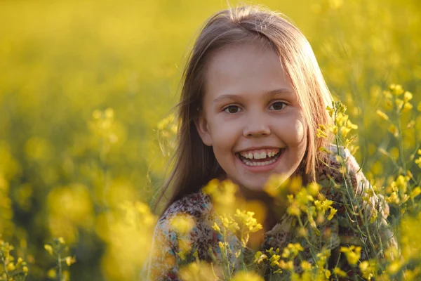 Begreppet hälsa och ungdom. Porträtt av en bekymmerslös ung flicka, att njuta av solnedgången i en raps fält. Stockbild