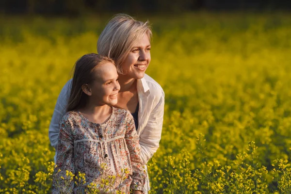 The concept of parenting. Beautiful mother and daughter on a yellow rape field Stock Photo