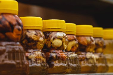 Çiftlik pazarında taze organik bal bulunan bir sürü kavanoz. Kavanozda meyveli ve fındıklı renkli bal, Altai 'de bir markette..