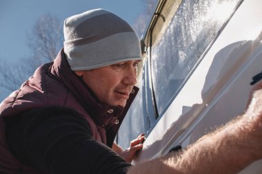 Bir adam dışarıda beyaz, kirli arabayı yıkar. Araba bakımı