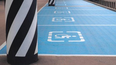 Uluslararası engelliler sembolü bir alışveriş merkezi park yeri üzerinde parlak mavi boyalı.