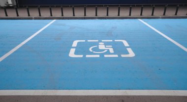 Uluslararası engelliler sembolü bir alışveriş merkezi park yeri üzerinde parlak mavi boyalı.