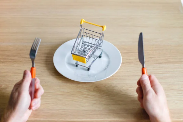 Plug and knife in hands on white background with plate. The concept of buying food in the supermarket.