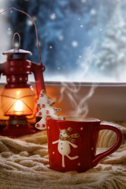 Kırmızı yağ lambası ve akşam pencere bir kardan adam arka planı ile Noel fincan.