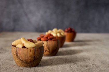Fındık, mahun cevizi, Brezilya fındık ve badem ahşap kase gri bir arka plan üzerinde.