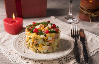 Bir beyaz tabak ve çatal bıçak takımı masanın üzerine Rus salatası.