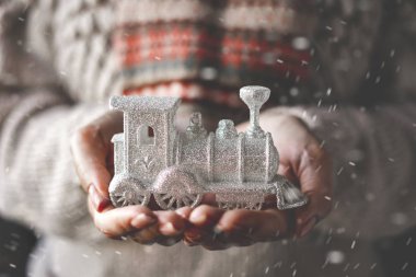 Bej örme kazak bir kadın elinde bir Noel dekoratif süs tutar - gümüş buharlı lokomotif.