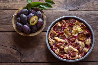 Ahşap bir arka planda kasede erik turtası ve taze erikler..