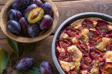 Ahşap bir arka planda kasede erik turtası ve taze erikler..