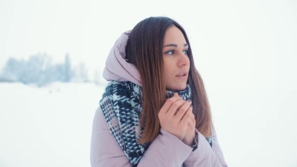 Bella ragazza cercando di riscaldare le sue mani congelate con un respiro in inverno mattina all'aperto . — Video Stock