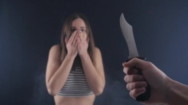 Manyak kız bir bıçakla tehdit ediyor. Umutsuz durum. Kız tehlikede gözleri elleriyle kapsar..