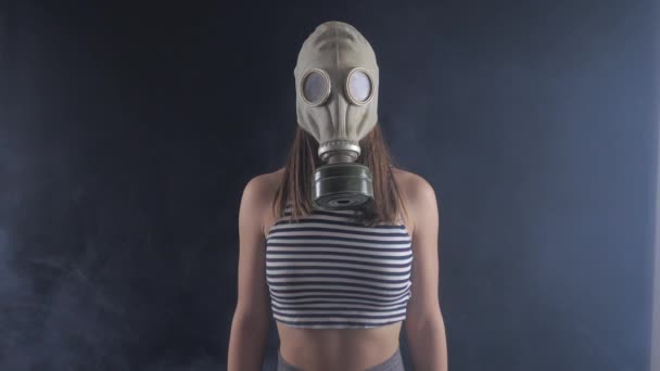 Portret van een vrouw in een gasmasker in rokerige donkere kamer. — Stockvideo
