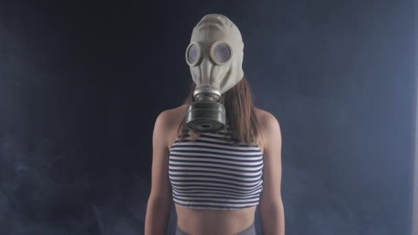 Portret van een vrouw in een gasmasker in rokerige donkere kamer. — Stockvideo