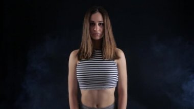 Çizgili üst baştan çıkarıcı kız duman karanlık bir odada duruyor.