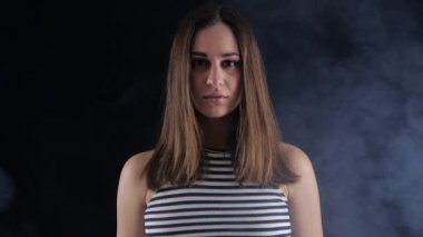Kız duman karanlık bir odada duruyor. Düz bak. uyuşuk.