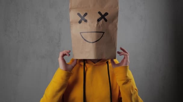 Brunette young girl in a yellow sweatshirt puts a paper bag over her head and dancing. 4k — Stock Video