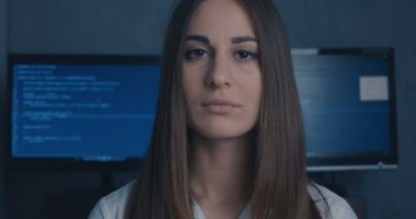Genç kadın geliştirici programcı ikili kod arka planda kamera bakıyor. 4k