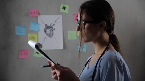 Porträt einer schönen Doktorandin mit Brille bereitet eine Präsentation vor, auf grauem Hintergrund. Konzept: Ideen, Schule, Universität, Wissenschaft, Lehrer, Gedächtnis, Biologie, Arzt, Hochschule — Stockvideo