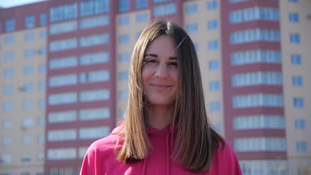 Portret van een jonge vrouw in een stad op de achtergrond woongebouw. 4k — Stockvideo