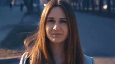 Closeup portre genç kız yolun arka planında karşı gülümseyen. Yoldan geçen arabalar. Gün batımı ve sıcak bir flaş kadın yüzünde dolaşmak.