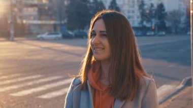 yakın çekim portre genç kız şehir arka plan üzerinde gülümseyen. Gün batımı ve sıcak parlama kadın yüzü üzerinde dolaşmak vardır.