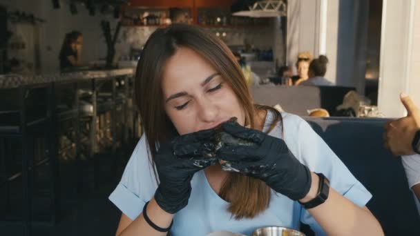 Menina com fome comer hambúrguer no restaurante Fast Food. 4K câmera lenta . — Vídeo de Stock