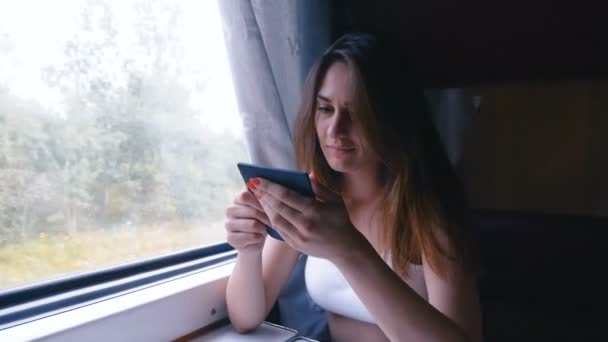 Mujer pensativa relajándose y mirando por la ventana de un tren y leyendo un libro. Vista lateral. Viajes, concepto de transporte — Vídeos de Stock