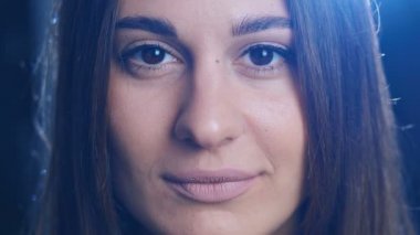 Yakın plan portre kadını. Genç bir kadın stüdyoda kameraya bakıp gülümsüyor. 4k