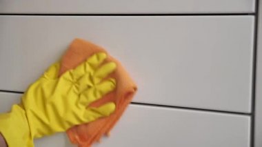 Odayı temizlemek, beyaz yüzeyi sarı eldivenler ve turuncu bir bezle silmek..