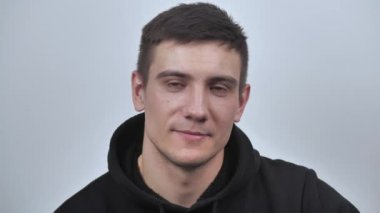 Çekici adam kameraya bakarak samimi bir şekilde gülümsüyor, beyaz bulanık arka planda izole edilmiş. Kapatın. 4k