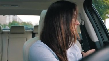 Genç bir kadın araba kullanmadan önce emniyet kemerini takıyor.