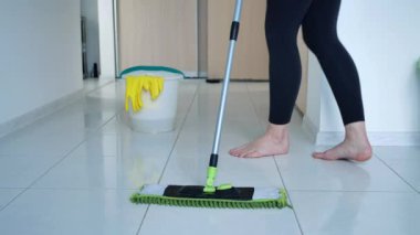 Beyaz mutfak zeminini sprey boyayla yıkayan kadın, temizlik servisi, yakın çekim.