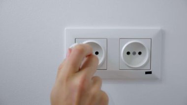 Kadın beyaz bir duvardaki elektrik prizine takar