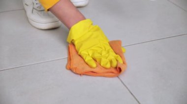 Sarı eldivenli bir kadın eli ahşap yüzeyi siler. Kapat..