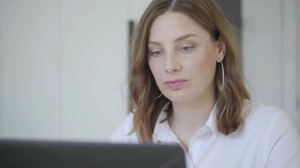 Primer plano, mujer caucásica con ojos verdes trabaja detrás de un ordenador portátil. — Vídeo de stock