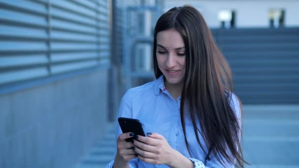 Młoda Atrakcyjna Dziewczyna Wyglądająca Niesamowity Holding Telefon komórkowy Czatowanie i śmiech w tle miasta. — Wideo stockowe
