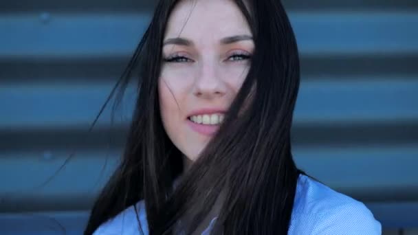 Zbliżenie portret atrakcyjna kobieta pozuje dla w kamery kobieta wyprostowuje jej włosy mruga i flirtuje w miasto tło. — Wideo stockowe