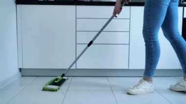 Beyaz mutfak zeminini sprey boyayla yıkayan kadın, temizlik servisi, yakın çekim.