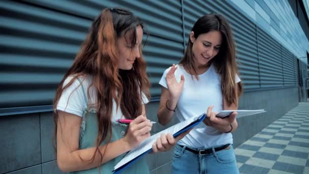 Duas jovens meninas de negócios conduzem negociações de negócios perto do centro de negócios. Trabalho, negócios. 4k — Vídeo de Stock