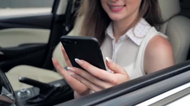 Kafkasyalı genç bir kadının park yerinde internette akıllı telefon sörfü yaparken parmak görüntüsünü kapat.