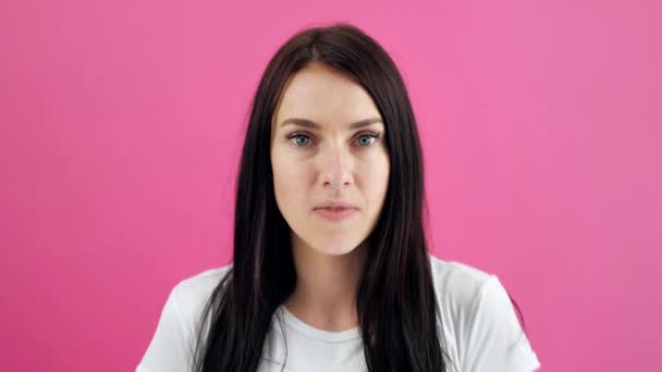 Verrast jonge, brunette vrouw die haar mond open houdt terwijl ze naar de camera staart, geïsoleerd op een roze achtergrond. Emotionele, aantrekkelijke vrouw met open mond is geschokt, verrast — Stockvideo