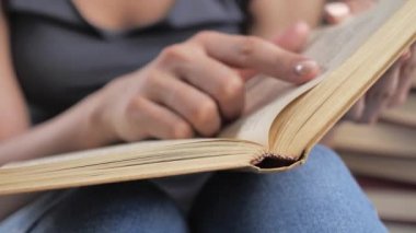 Bir kadın bir kitabı tutar ve okurken parmaklarını sayfa boyunca hareket ettirir. El ve kitap: bir kitap okumak ve parmaklarını çizgiler boyunca tutmak. Kitabın okuyucusunda 4K var.