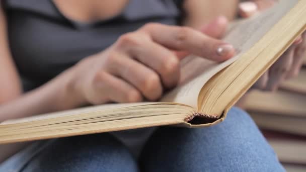 Uma mão de mulher segura um livro e move os dedos ao longo da página enquanto lê. Mão e livro: lendo um livro e segurando os dedos ao longo das linhas. O leitor do livro detém 4k — Vídeo de Stock