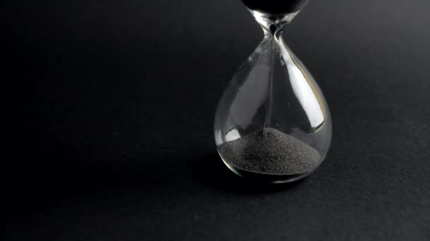 Пісочний годинник з чорним піском виходить, безжальний час летить швидко, повільно рухаючись. 4k — стокове відео